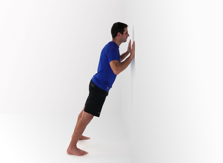 A man doing a mini push-up against a wall